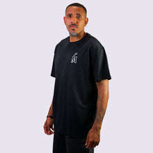 Load image into Gallery viewer, Man wearing a black t-shirt with a logo on a light gray background