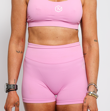 Load image into Gallery viewer, Person wearing a pink sports outfit with a visible brand logo on a plain background
